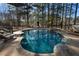 Backyard swimming pool featuring natural stone surround, lounge chairs, mature trees, and ample deck space at 183 Applewood Ln, Acworth, GA 30101