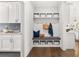 Mudroom featuring a bench with built-in storage, hanging hooks, white cabinets with laundry sink, and hardwood floors at 3709 Tielman St, Snellville, GA 30078