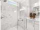 Close up of glass shower with white marble tile, a shower bench, and modern white cabinets with double sinks at 3709 Tielman St, Snellville, GA 30078