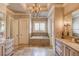 Luxurious bathroom featuring a soaking tub, double vanities, and a chandelier at 922 Little Darby Ln, Suwanee, GA 30024