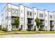 Modern townhome exterior with white and gray facade, accented by manicured landscaping and young trees at 3072 Kelly St, Scottdale, GA 30079