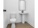 Elegant half bathroom with modern pedestal sink and wood-look flooring at 6210 Misty Hill Ln, Buford, GA 30518