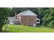 Rear exterior view of a two-story brick home with deck and fenced backyard, surrounded by lush trees at 1294 Dogwood Rd, Snellville, GA 30078