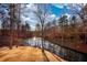 A serene pond surrounded by mature trees and foliage reflects the sky, creating a peaceful backyard setting at 3411 Deer Sw Trce, Conyers, GA 30094