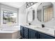 Bathroom featuring double sink vanity, large soaking tub, and bright natural light at 125 Cinnamon Fern Cir, Covington, GA 30016