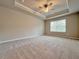 Large main bedroom with carpet flooring, tray ceiling with ceiling fan and window at 5435 Rock Place Ct # 38, Norcross, GA 30093