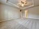 Large main bedroom featuring neutral walls and carpet, a ceiling fan, and a tray ceiling at 5435 Rock Place Ct # 38, Norcross, GA 30093