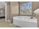 Main bathroom with soaking tub and a window overlooking the backyard at 3945 Brushy Creek Way, Suwanee, GA 30024