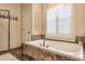 Relaxing bathroom with soaking tub, tile surround, and a window with shutters at 1103 Ridenour Ct, Kennesaw, GA 30152