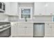 Modern kitchen with white cabinets, gray backsplash, and stainless steel appliances at 2836 Crescendo Dr, Atlanta, GA 30318