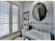 Charming powder room with a pedestal sink, an oval mirror, and plantation shutters at 5890 Bond St, Cumming, GA 30040