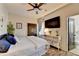 Cozy bedroom with a large bed, television, ceiling fan, a small table with storage, and a door to the private bathroom at 5890 Bond St, Cumming, GA 30040