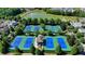 Aerial view of a community with multiple tennis courts near a lake and surrounded by lush greenery at 5890 Bond St, Cumming, GA 30040