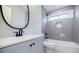 Modern bathroom features a gray vanity, round mirror, gray tile in shower/tub, and sleek fixtures at 59 Stafford Nw St, Atlanta, GA 30314