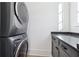 Laundry room with stacked washer and dryer and dark gray cabinets at 10861 Serenbe Ln, Chattahoochee Hills, GA 30268