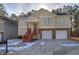 Tan two-story house with two car garage, red stairs and landscaping at 113 Omega Ct, Dallas, GA 30157