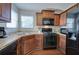 Kitchen with corner sink, dark wood cabinets and black appliances at 113 Omega Ct, Dallas, GA 30157