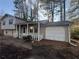 Tan house with a covered porch, white railing, and attached garage at 5451 Zachary Dr, Stone Mountain, GA 30083