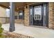 Covered front porch with brick columns and a black front door at 654 Ocean Ave, Canton, GA 30114