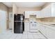 Kitchen boasts white cabinets, tile floors, and black appliances at 6691 Sunset Hills Blvd, Rex, GA 30273