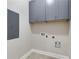 A functional laundry space with overhead gray cabinets, light tile flooring, and necessary hookups at 199 Racine Sw St, Atlanta, GA 30314