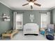 Well lit Bedroom featuring a crib, toy car track table, chair with toys, neutral walls, and ceiling fan at 1399 Knob Hill Se Ct, Atlanta, GA 30316