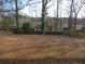 Partially fenced backyard with mature trees and leaf covered ground at 2491 Crestdale Se Cir, Atlanta, GA 30316