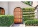 Elegant arched wood door entryway with well-manicured hedges on either side at 23 Paces West, Atlanta, GA 30327