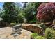 Flagstone patio with stone retaining wall and wrought iron patio furniture, surrounded by mature landscaping and trees at 23 Paces West Dr, Atlanta, GA 30327