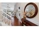 Inviting hallway with hardwood floors, staircase and a round decorative mirror on a dark wood table at 535 Cape Ivey Dr, Dacula, GA 30019