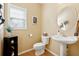 Small half bathroom with pedestal sink, toilet, and beige walls at 724 Landsdowne Ln, Locust Grove, GA 30248