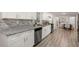 White shaker cabinets, granite countertops, and gray-toned wood flooring at 1352 Jennie Sw Ln, Lilburn, GA 30047