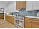 Modern kitchen with stainless steel range, light wood cabinets, and blue tile backsplash at 1565 Pineview Terrace Sw, Atlanta, GA 30311