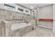 Soaking tub and shower with neutral tile, windows and hardwood accents at 4847 Lakewood Dr, Acworth, GA 30101