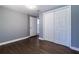 A modern bedroom with gray walls, wood-look floors, a closet with sliding doors, and a white door that leads to another room at 1268 Kenilworth Sw Dr, Atlanta, GA 30310