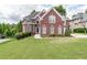 Brick house with a large green lawn and driveway at 2080 Misty Oaks Dr, Buford, GA 30519