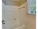 Bright white tiled tub/shower combo with a shower head and window with blinds at 3337 Devaughn Ne Dr, Marietta, GA 30066
