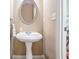 Small powder room with pedestal sink and oval mirror at 169 Blue Creek Ln, Loganville, GA 30052