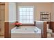 Relaxing bathroom with soaking tub, window, and brown wainscoting at 3398 Chatsworth Way, Powder Springs, GA 30127