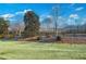 Manicured landscaping with lush green grass, decorative trees, and a charming wooden fence enhancing the property's curb appeal at 2475 Barley Crest Pass, Cumming, GA 30040
