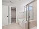 Bathroom featuring a soaking tub, glass-enclosed shower, neutral tile, and a window at 313 Foxglove Way, Mcdonough, GA 30253
