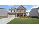 Charming two-story home featuring a brick facade, well-manicured lawn, and attached two-car garage at 313 Foxglove Way, Mcdonough, GA 30253
