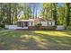 Charming single-story home with a brick foundation, screened porch, and a lush green lawn surrounded by mature trees at 1931 Oana Sw St, Atlanta, GA 30310