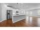 Open-concept kitchen with stainless steel appliances, a large island, white cabinets, and hardwood floors at 236 Begonia Way, Mcdonough, GA 30253