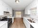 Galley style kitchen with white cabinets, light countertops, wood floors, and stainless steel appliances at 7018 Chimney Ridge Dr, Riverdale, GA 30296
