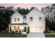Charming two-story white farmhouse with a covered front porch, landscaped yard, and an attached two-car garage at 319 Willam Gossett Dr, Canton, GA 30114