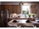 Close-up of kitchen island with stainless fridge, bar seating, sink, and window bringing in natural light at 319 Willam Gossett Dr, Canton, GA 30114