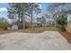 Large driveway and grassy backyard with a shed, framed by mature trees and distant houses at 1900 Gober Se Ave, Smyrna, GA 30080