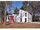 Stunning exterior of modern white house with black trim, red door, lush lawn, and natural wooded backdrop at 2645 Shadow Woods Ne Cir, Marietta, GA 30062
