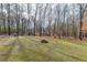 Wide open backyard area with mature trees, green space, and a fire pit at 2205 Castle Royale Dr, Lawrenceville, GA 30043
